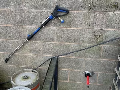 Outdoor connection point and pressure washer trigger gun installed for external cleaning at a Twycross farm.